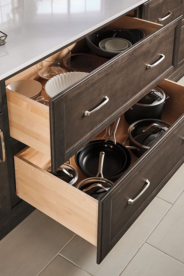 an open drawer with pots and pans in it on a counter top next to a sink