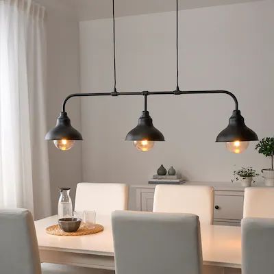 a dining room table with four lights hanging over it