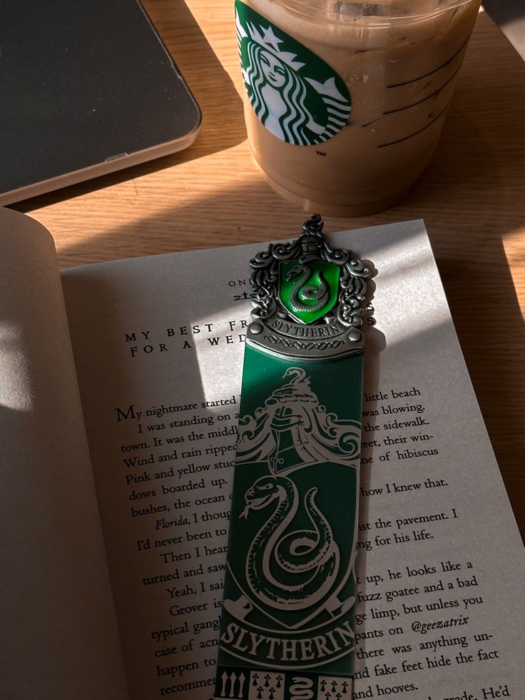 an open book on a table next to a starbucks drink