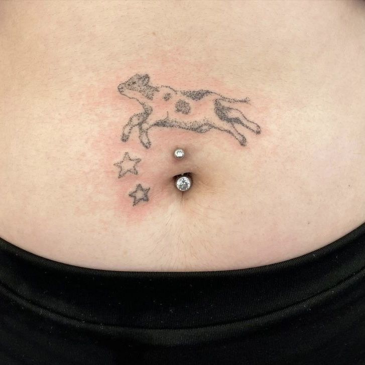 a woman's stomach with a small tattoo on the side of her belly that has stars and a dog