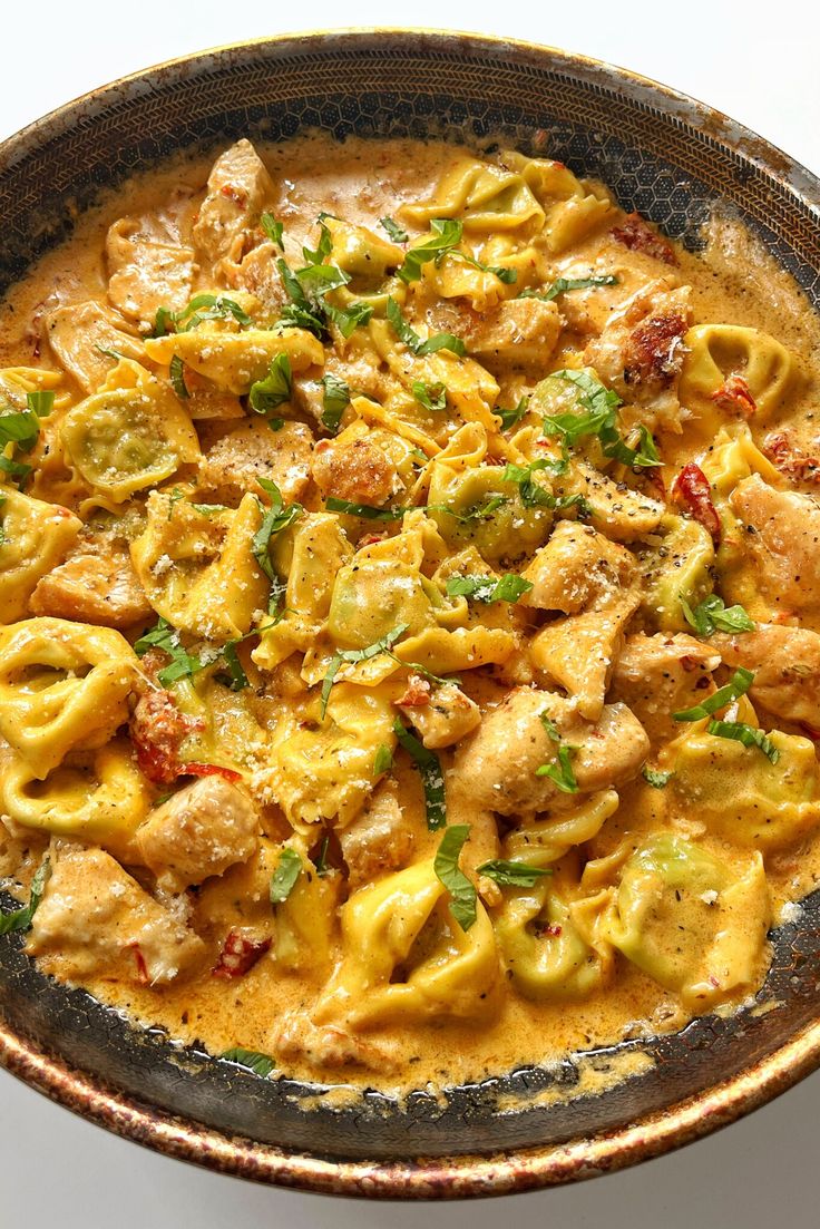 a bowl filled with pasta and meat covered in sauce on top of a white table