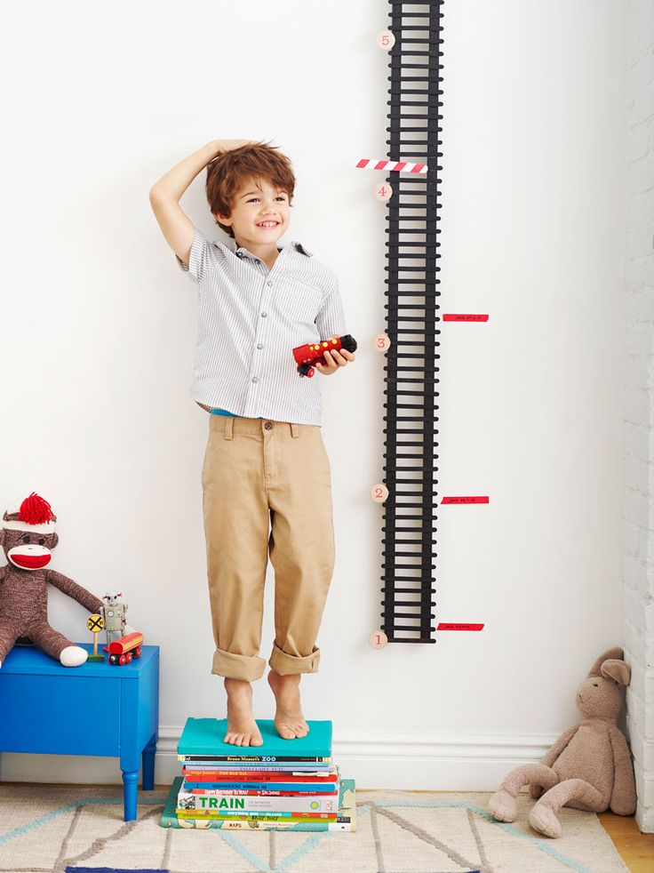 a young boy standing on top of books in front of a wall mounted book rack