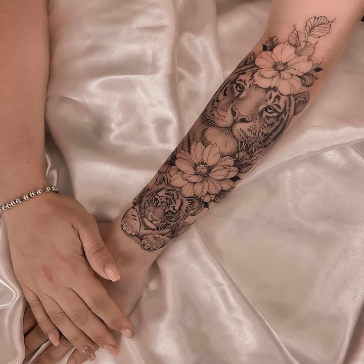 a woman's arm with flowers on it and a tiger in the middle is shown