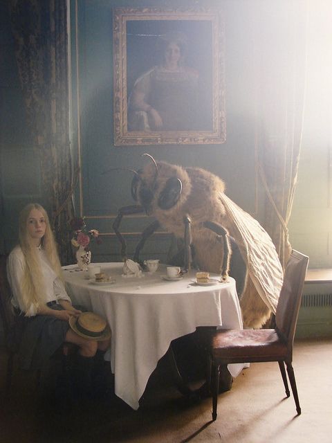 a woman sitting at a table in front of a painting