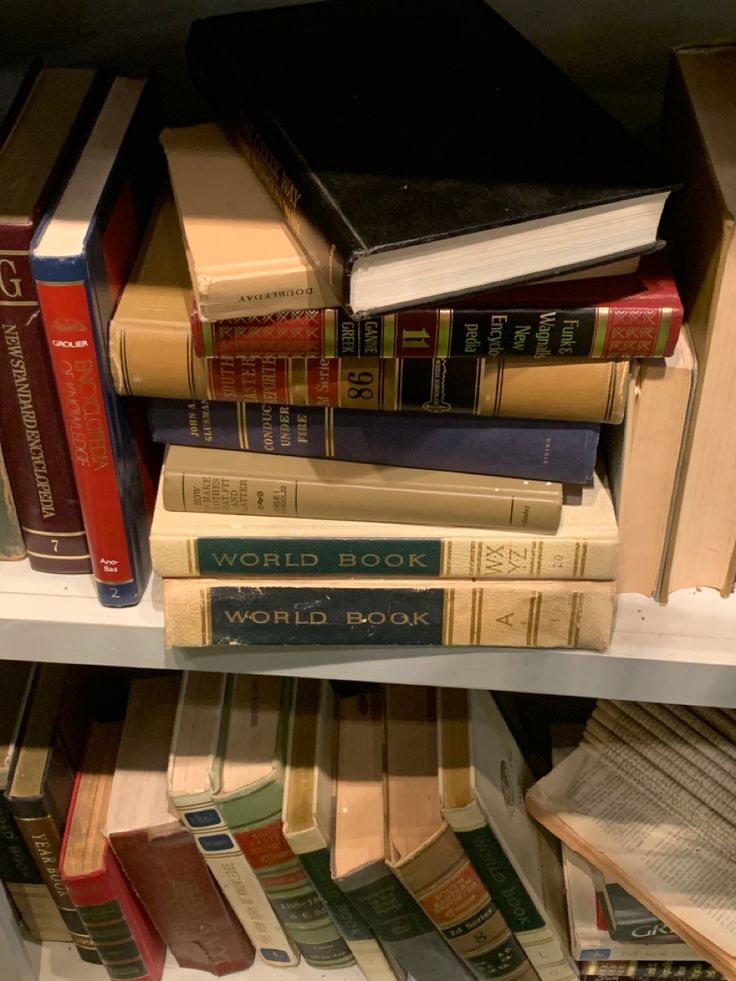 several books are stacked on top of each other in a bookcase, with one being read