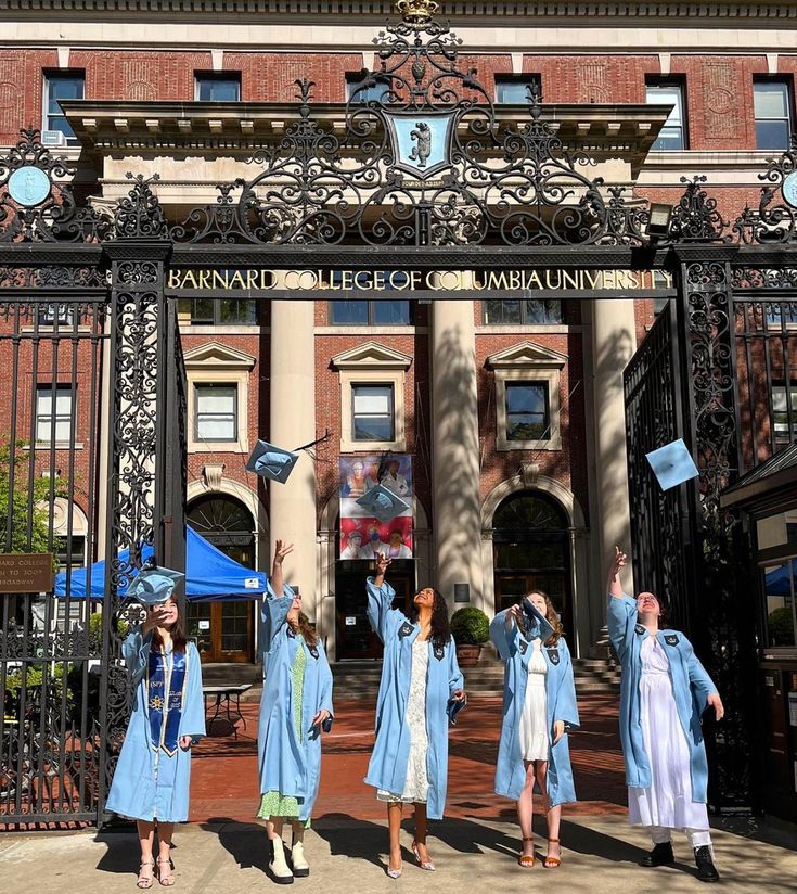 several people in blue graduation gowns are standing outside the entrance to an old building