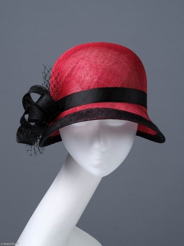 This small red hat was made for lovers of the style of the twenties of the last century. A deep head and a slight sloping brim are characteristic elements of these times. The wide trim perfectly marks the wavy shape of the brim, and the black ribbon and the bow on the right side complete the entire composition.  This headpiece is hand formed and sewed, making it an exclusive design. This artisan cocktail hat would perfectly compliment elegant outfit at a wedding or similar event. *Handmade item *Size: 57cm *Fabric : red black sinamay  *Ships worldwide from Poland *More products available on www.joremi.co.uk If you want to make minor changes or create your own design, I encourage you to do so. I am happy to create something especially for you.  All of my products are exclusively designed an Red Retro Party Hat, Retro Red Party Hat, Red Fedora With Curved Brim For Formal Occasions, Red Fedora Hat For Formal Occasions, Red Formal Fedora Hat, Red Vintage Mini Hats With Curved Brim, Red Brimmed Fedora For Formal Occasions, Red Short Brim Fedora For Formal Occasions, Red Retro Hat With Curved Brim