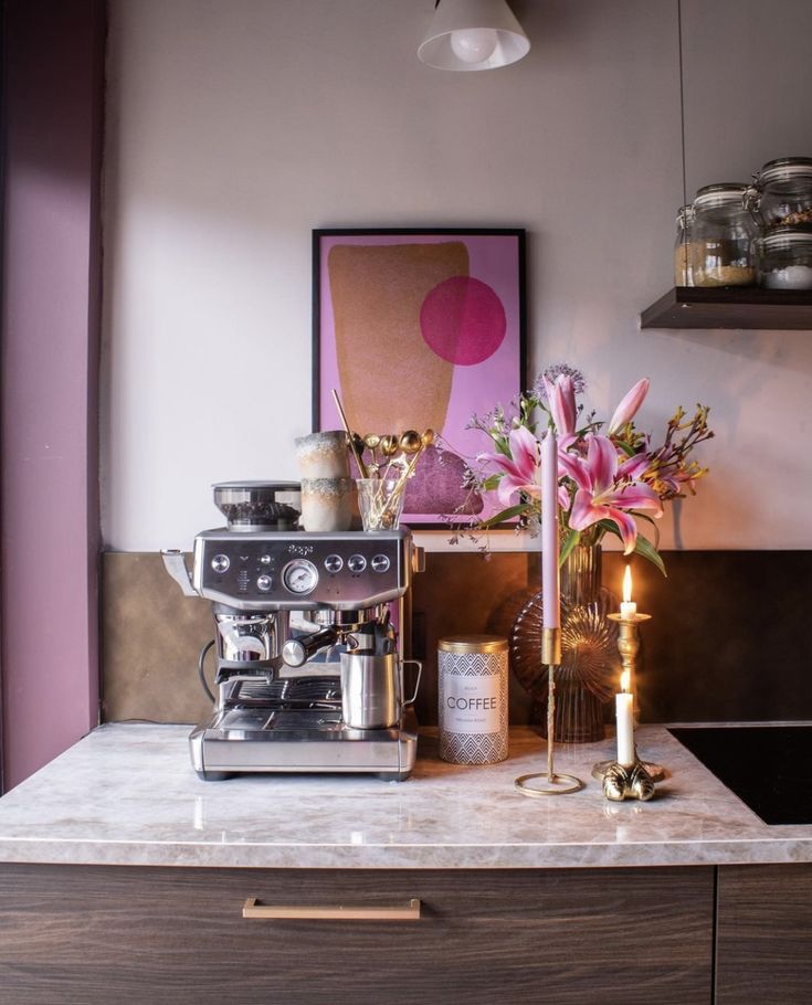 a kitchen counter topped with a coffee maker and vase filled with flowers on top of it