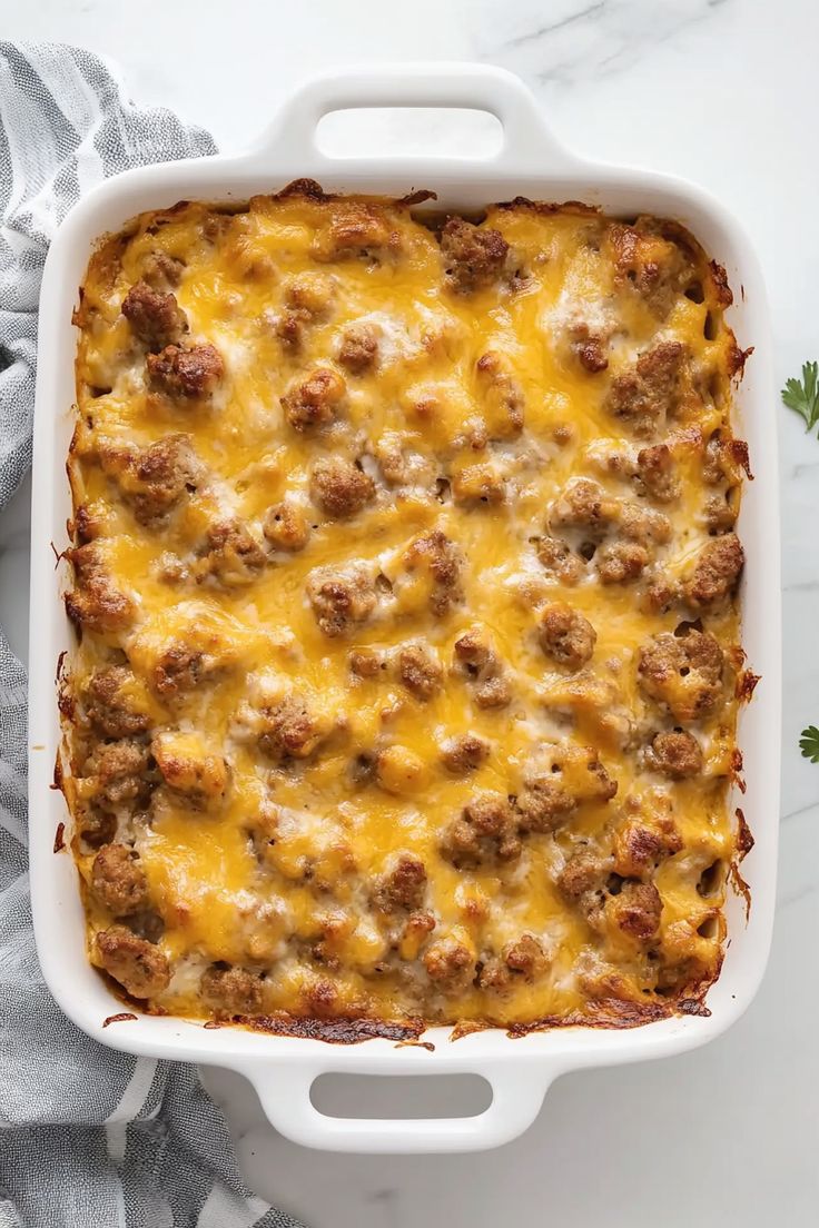 a casserole dish with meat and cheese in it on a white tablecloth