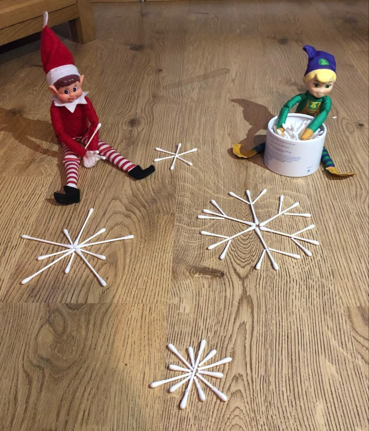 two elfs are sitting on the floor with snowflakes