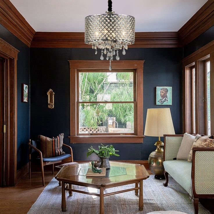 a living room filled with furniture and a chandelier hanging from the ceiling next to a window