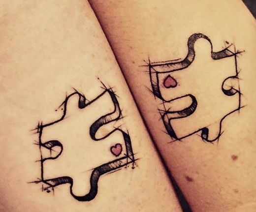 two people with matching tattoos on their legs, one has a heart and the other has a puzzle piece