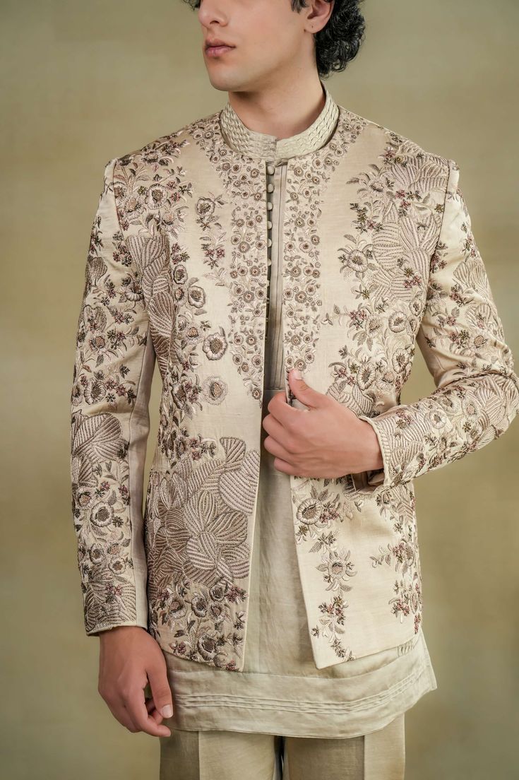 Sand Grey Short Jacket | Jatin Malik Introducing our sand grey short jacket, adorned with exquisite hand-embroidery details for a touch of sophistication and style. This versatile piece is paired with a matching short kurta and tapered trousers, creating a sleek and modern ensemble that exudes effortless charm. Perfect for both formal and semi-formal occasions, this outfit is sure to make a statement with its understated elegance and impeccable craftsmanship. Included in purchase: Short Jacket, Kurta, Trousers Product Specification Color: Sand Grey Fabric: Linen Silk Occasion: Engagement, Wedding, Bridal, Reception Style: Short Jacket, Kurta, Trousers Care: Dry Clean Work: Hand Embroidery Customization options:Can be customized in any color or style Note: A stylist will contact you to conf Reception Bandhgala With Floral Embroidery And Long Sleeves, Elegant Bandhgala With Floral Embroidery And Traditional Drape, Long Sleeve Nehru Jacket With Intricate Embroidery For Reception, Floral Embroidered Long Sleeve Nehru Jacket For Reception, Long Sleeve Outerwear With Intricate Embroidery For Reception, Festive Wedding Sets With Tonal Embroidery, Designer Long Sleeve Nehru Jacket With Intricate Embroidery, Designer Long Sleeve Nehru Jacket With Embroidery, Elegant Outerwear With Chikankari Embroidery For Eid