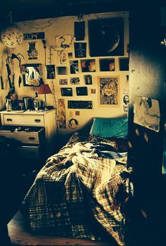 a bed sitting in a bedroom next to a wall covered in pictures and posters on it