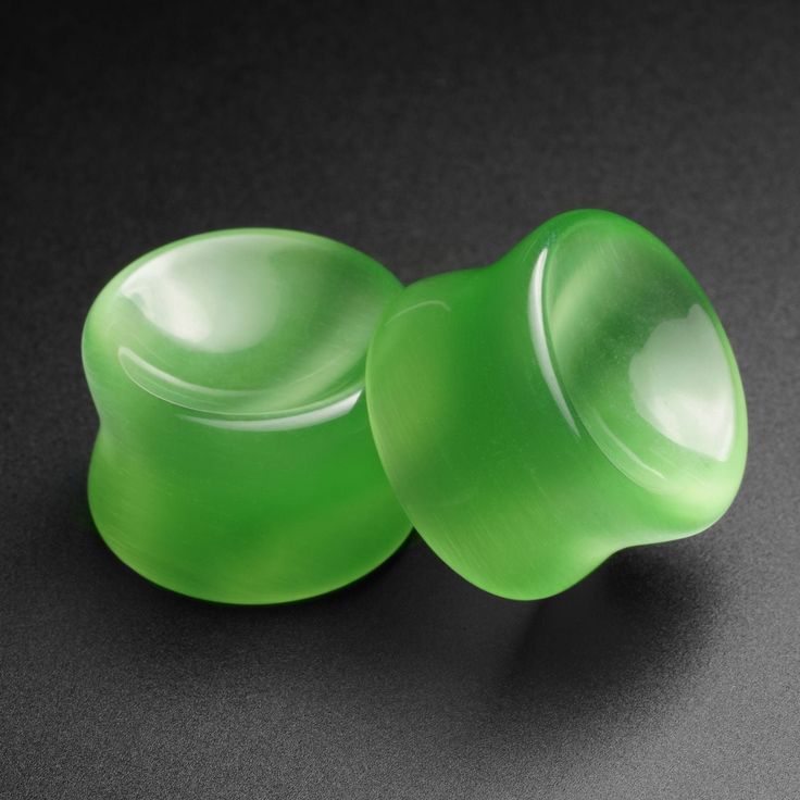 two green glass knobs sitting on top of a black table next to each other