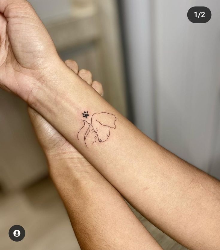 two hands holding each other with a small tattoo on the wrist that has a dog's paw in it