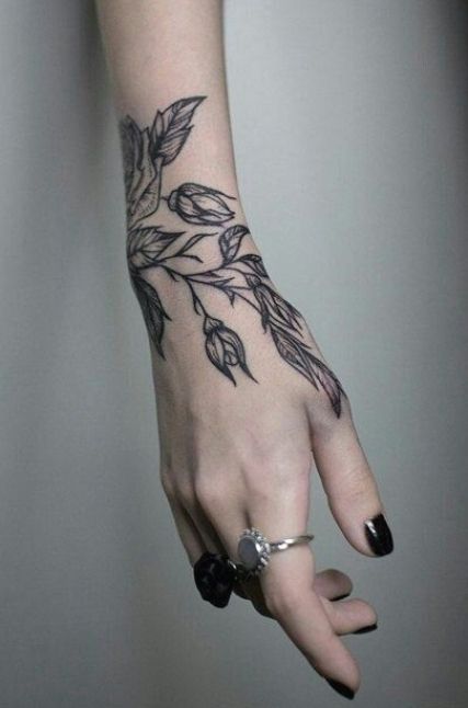 a woman's hand with a tattoo on it and some leaves around her wrist