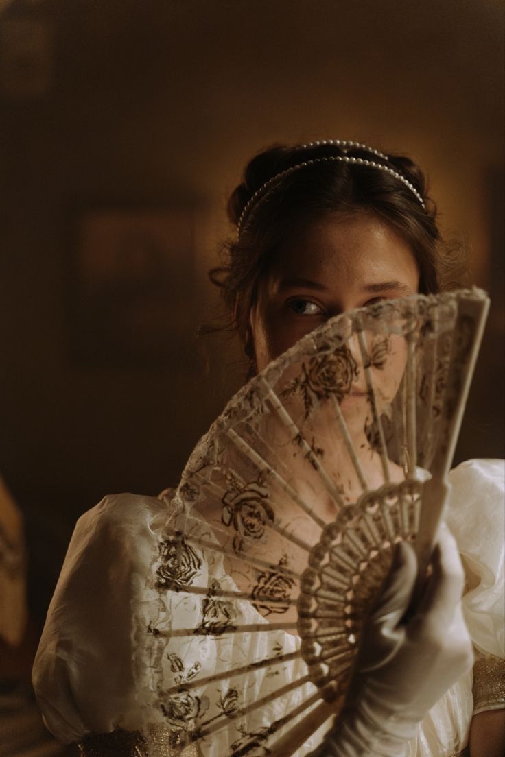 a woman holding a fan in her hands