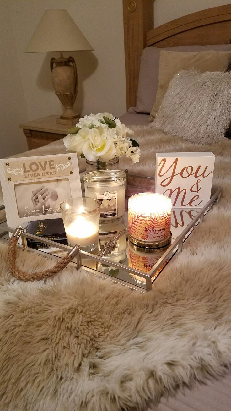 a tray with candles, flowers and cards on it sitting on a bed in a bedroom