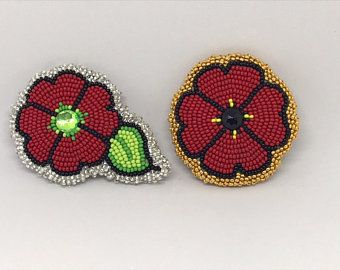 two red and green beaded flower brooches, one with a leaf on it