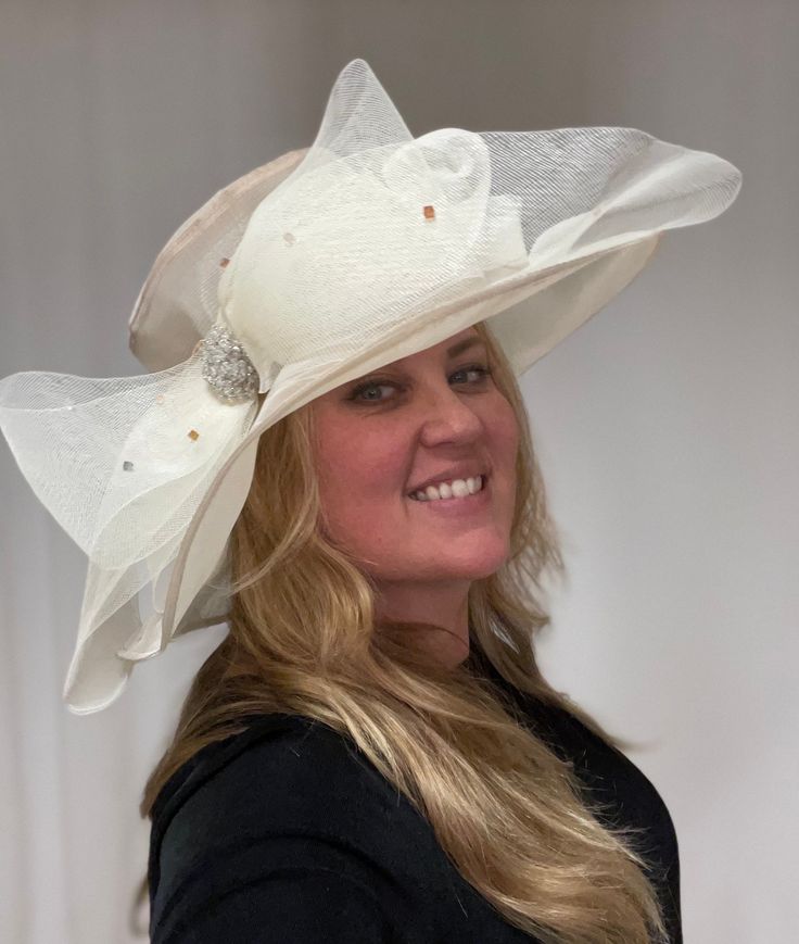 This is a beautiful neutral beige colored sheet hat. This stunning large brimmed hat does have an adjustable string on the inside, so this hat is one size fits all. There is a large sheer bow with gorgeous crystals all over it and clustered in the center. This is a gorgeous, elegant hat. Elegant Cream Hat With Bow, Adjustable Cream Sun Hat For Wedding, Chic Beige Hat With Bow, Adjustable Cream Hat For Evening, Elegant Adjustable Hat With Bow, Elegant Hat With Bow And Curved Brim, Elegant Adjustable Cream Sun Hat, Elegant Cream Fedora Hat, Elegant Cream Sun Hat For Wedding