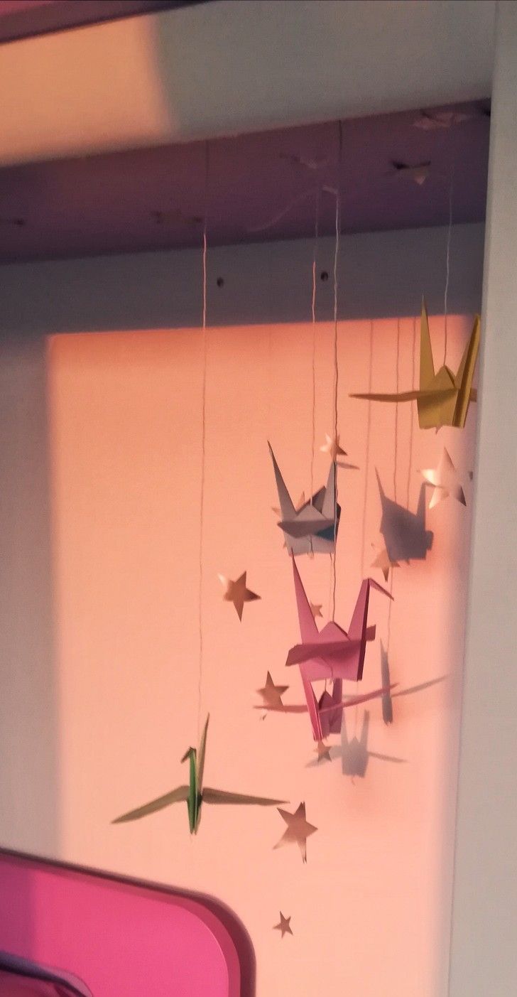 an origami mobile hanging from the ceiling in a room with pink walls and stars