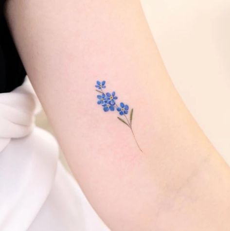 a small blue flower tattoo on the arm