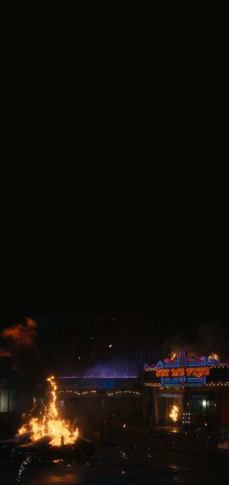 fireworks are lit up in the night sky near a building with an illuminated sign on it