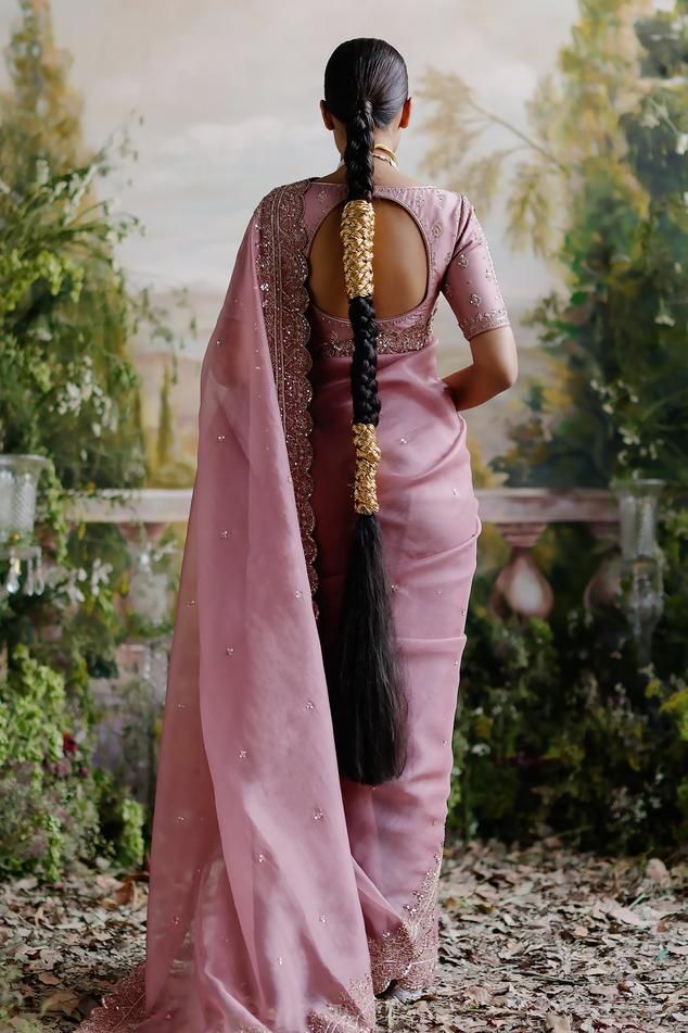 a woman in a pink sari with long braids on her head and back