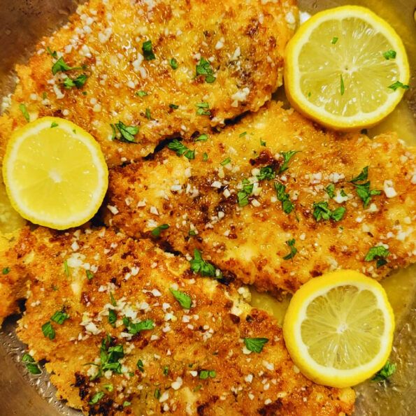 fried fish with lemons and parmesan cheese on a metal pan, ready to be eaten