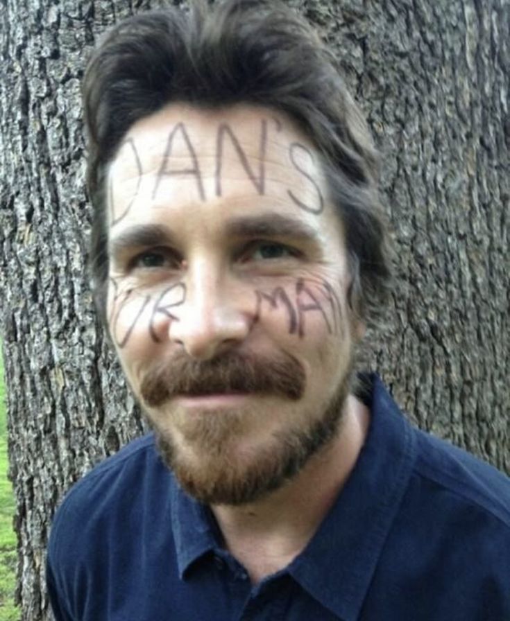 a man with words written on his face next to a tree