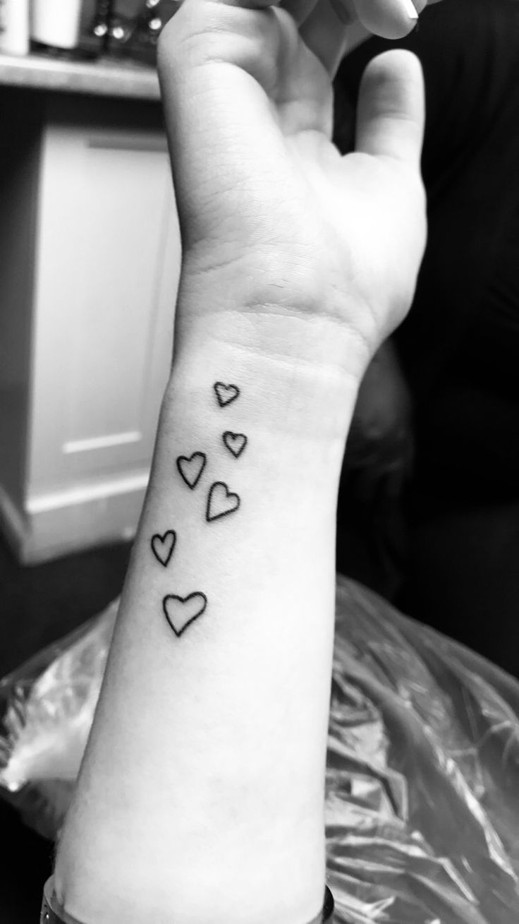 a woman's arm with four hearts on it and the word love written in black ink