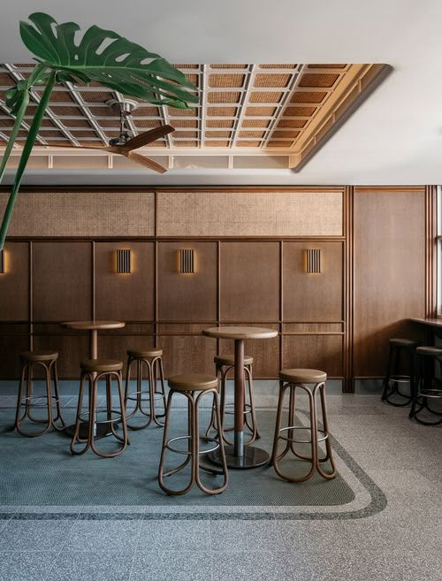 an empty room with several stools and tables in front of a plant on the floor