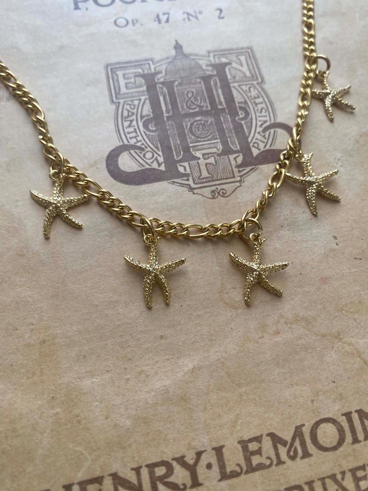 A detailed gold-plated starfish charm necklace. The starfishes measures 1.4 cm x 1.6 cm. Hung on a 16 inch gold-plated chain over stainless steel chain. Comes in a black velvet cushioned box, free of charge. Matching earrings available here.... https://zarataylor.etsy.com/uk/listing/1739294657/gold-starfish-huggie-hoop-earrings INTERNATIONAL BUYERS please choose the tracking option if you would like your order to be tracked. FREE tracking upgrade with 3 items or more purchased. JEWELLERY CARE pl Gold Starfish Clavicle Chain Necklace, Gold Starfish Charm Jewelry, Gold Starfish Charm Necklace Gift, Gold Necklace With Starfish Charm For Gift, Gold Jewelry With Starfish Charm As A Gift, Gold Starfish Necklace With Lobster Clasp, Gold Jewelry With Starfish Charm For Gift, Gold Charm Necklaces With Starfish Charm As A Gift, Gold Star Charm Necklace With Lobster Clasp