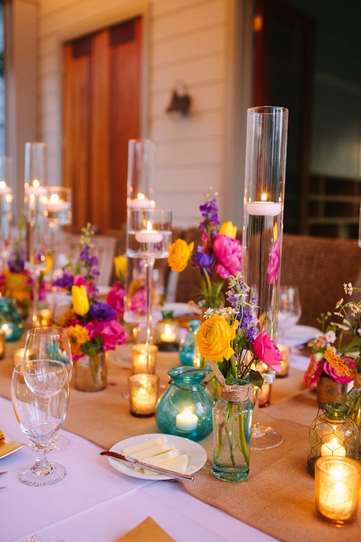 the table is set with candles, flowers and vases for dinner guests to enjoy