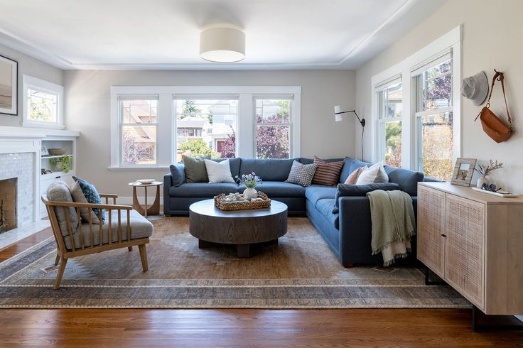 a living room filled with furniture and a fire place in front of a window on top of a hard wood floor