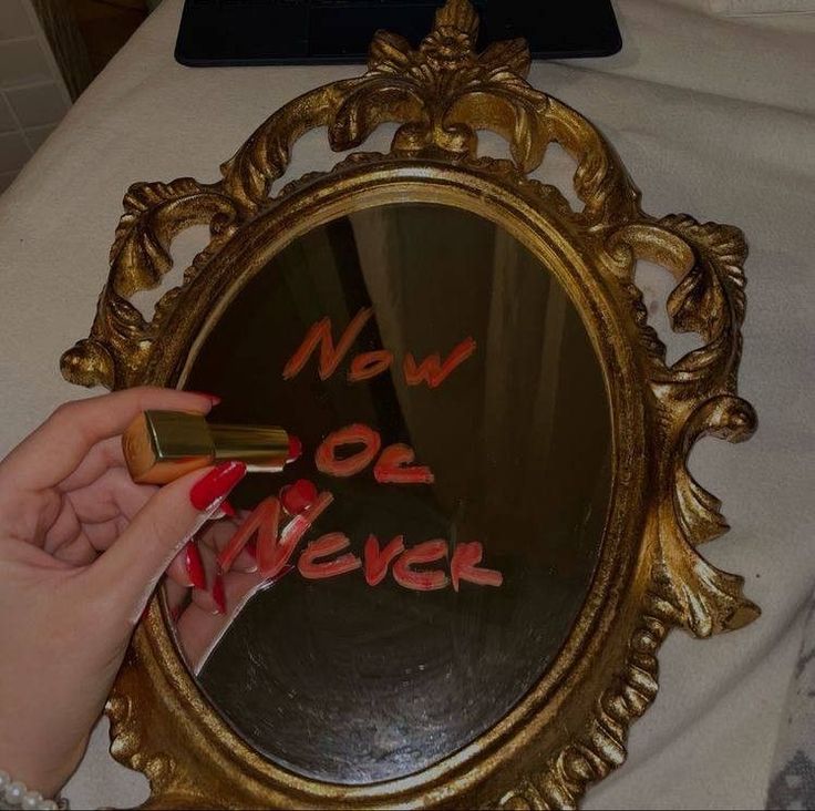 a person holding a lipstick in front of a mirror that says, now or never