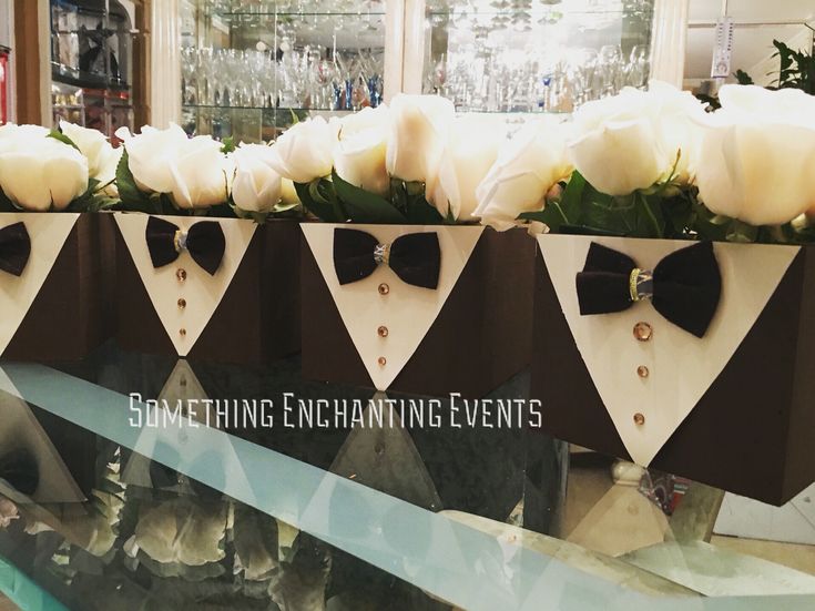 some white roses and black bow ties on display in a store window with the words something enchanting events