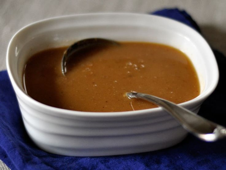 a white bowl filled with soup on top of a blue cloth next to a spoon