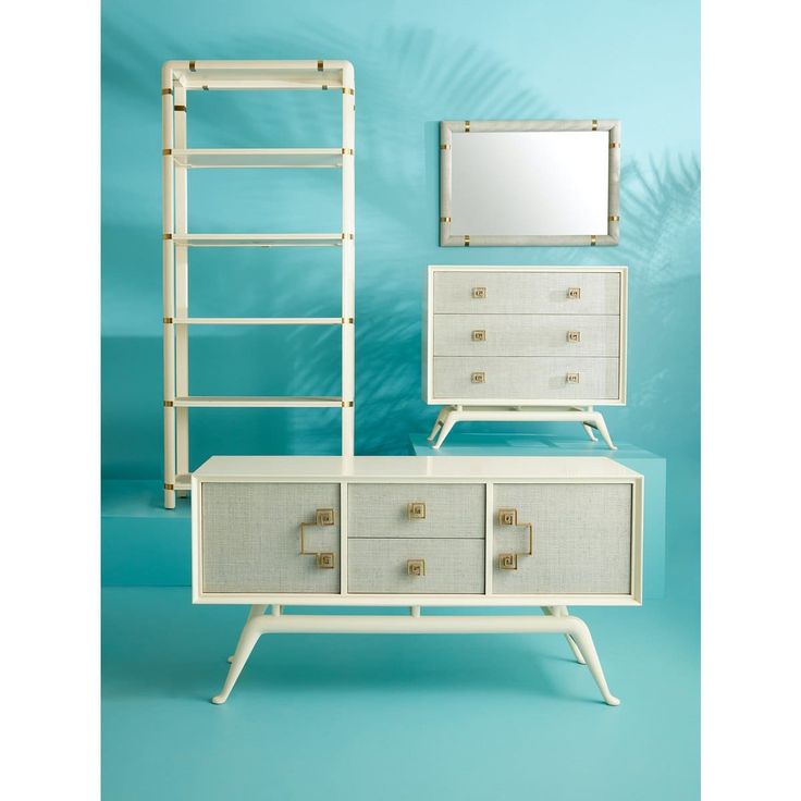 a white dresser sitting next to a mirror on top of a blue wall