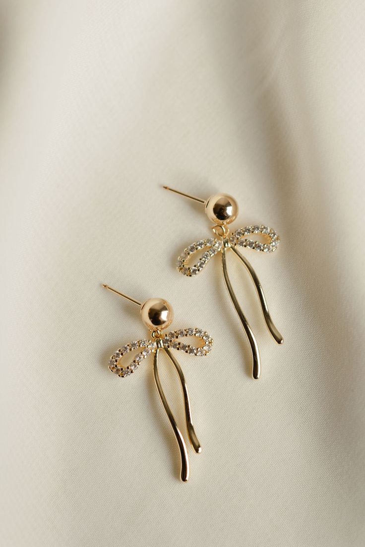 Rumor has is that 2024 is the year of BOWS! These super cute, dangly bow earrings will be the HIT of any party. Includes two gold or silver-plated CZ sparkly dangly bow charms with 6mm 14k gold-filled or sterling silver, hypoallergenic ball studs Gold Plated Sparkling Earrings For Gift, Sparkling Gold-plated Earrings For Gift, Gold Earrings With Dangling Charms For Party, Gold Party Jewelry With Dangling Charms, Gold Glamorous Jewelry With Bow, Glamorous Gold Jewelry With Bow, Trendy Dangling Charms Earrings For Party, Cute Bow Jewelry For Parties, Gold Dangle Jewelry With Bow