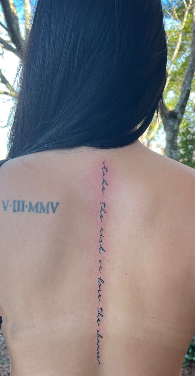 the back of a woman's shoulder with roman numerals on it