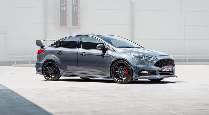 a grey car parked in front of a building with red rims on it's tires