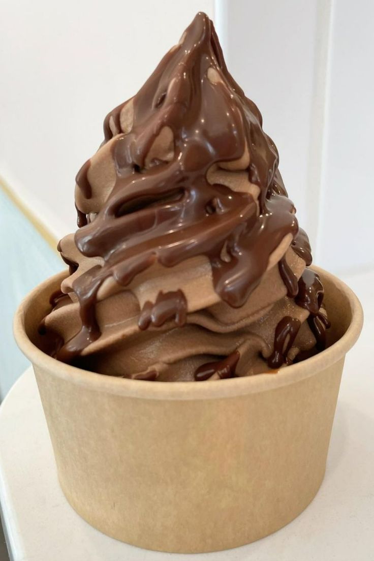 a bowl filled with chocolate ice cream sitting on top of a white counter next to a wall