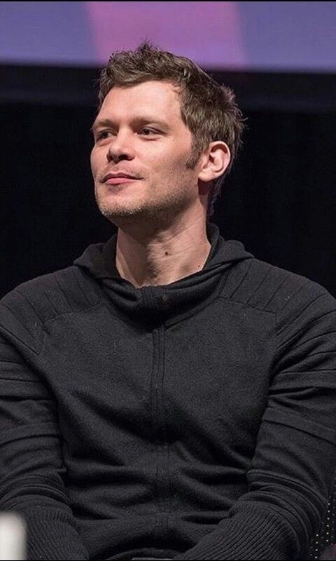 a man sitting in a chair with his arms crossed and looking off to the side