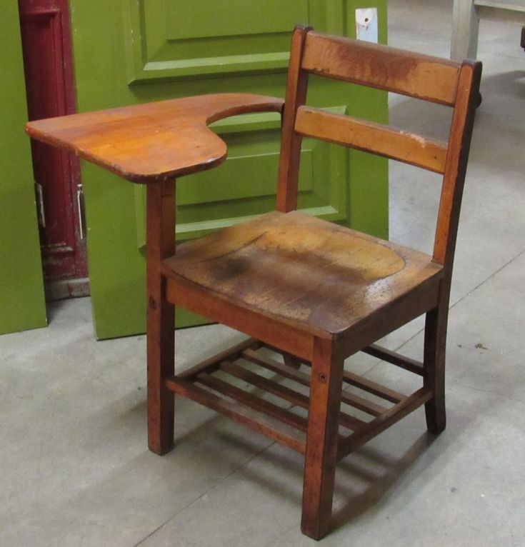 an old wooden chair sitting in front of a green door with the seat up on it's side