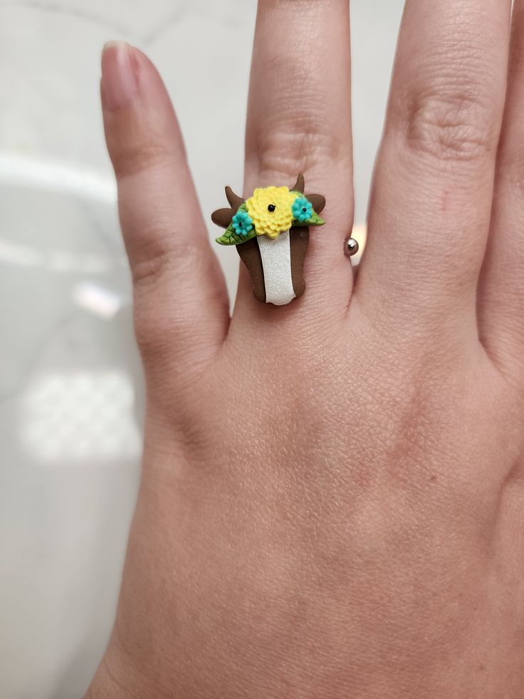 a person's hand with a yellow and green flower ring on top of it