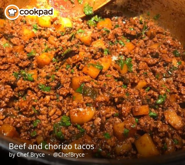 a pot filled with meat and vegetables on top of a stove next to a wooden spoon