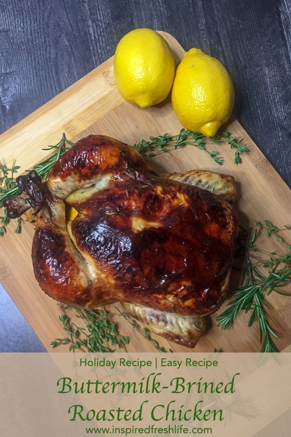 a roasted chicken on a cutting board with lemons and rosemary sprigs next to it