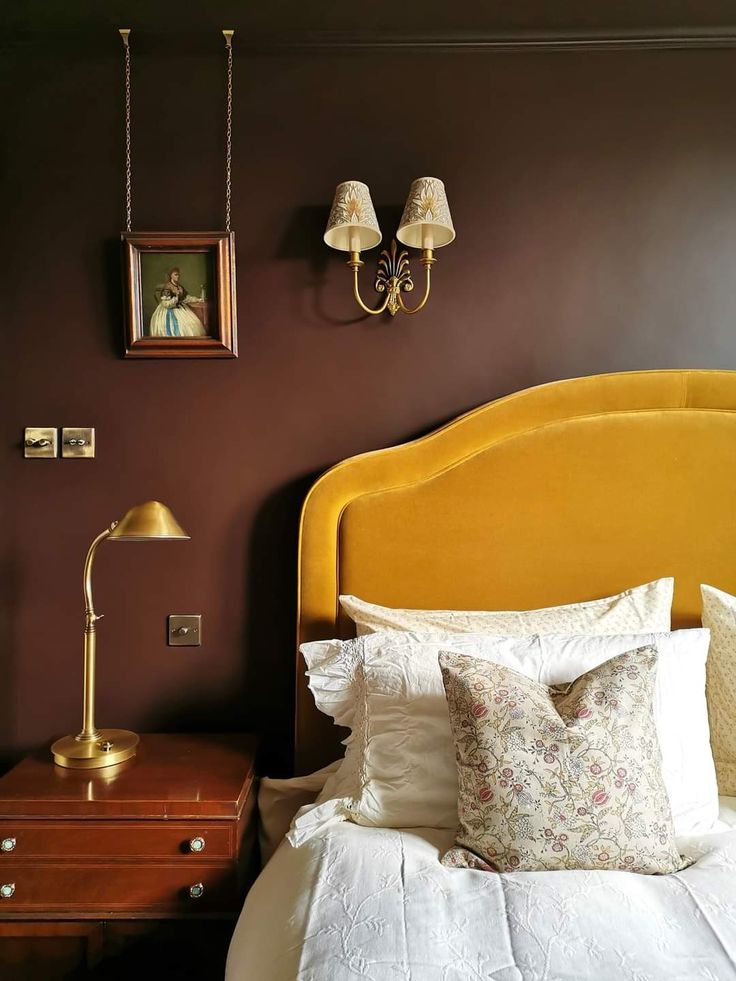 a yellow headboard in a bedroom next to a night stand with two lamps on it